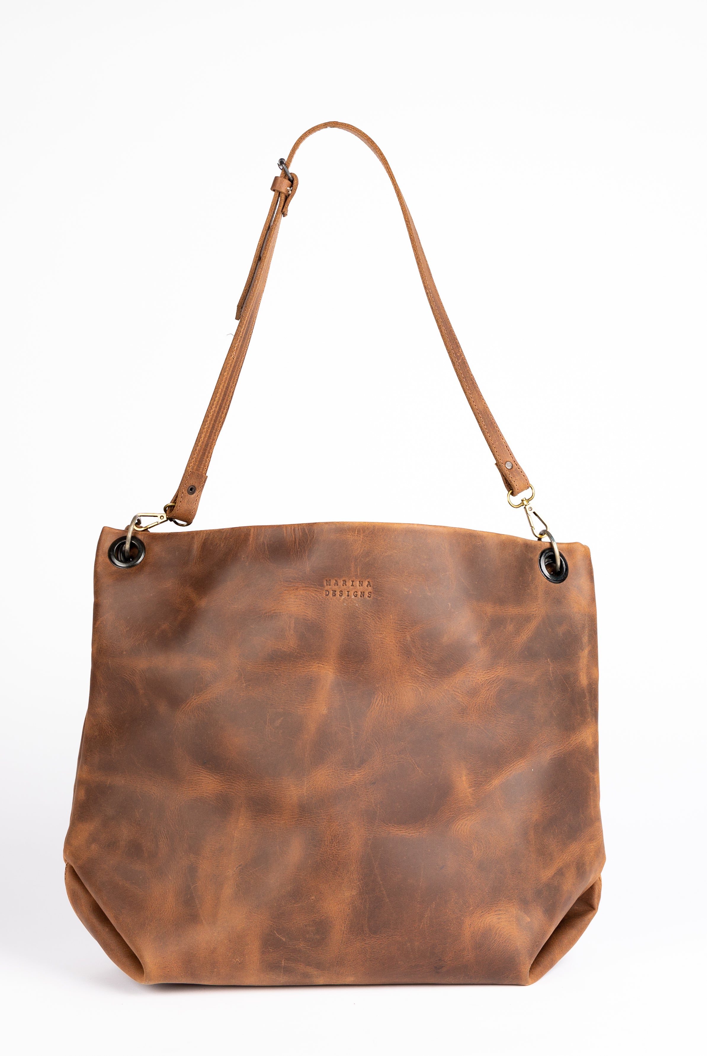 Straight-on view of the Parisian Tote, highlighting its smooth, full-grain castano leather and elegant minimalist shape. The adjustable shoulder strap is shown centered, with brass hardware and grommet details.