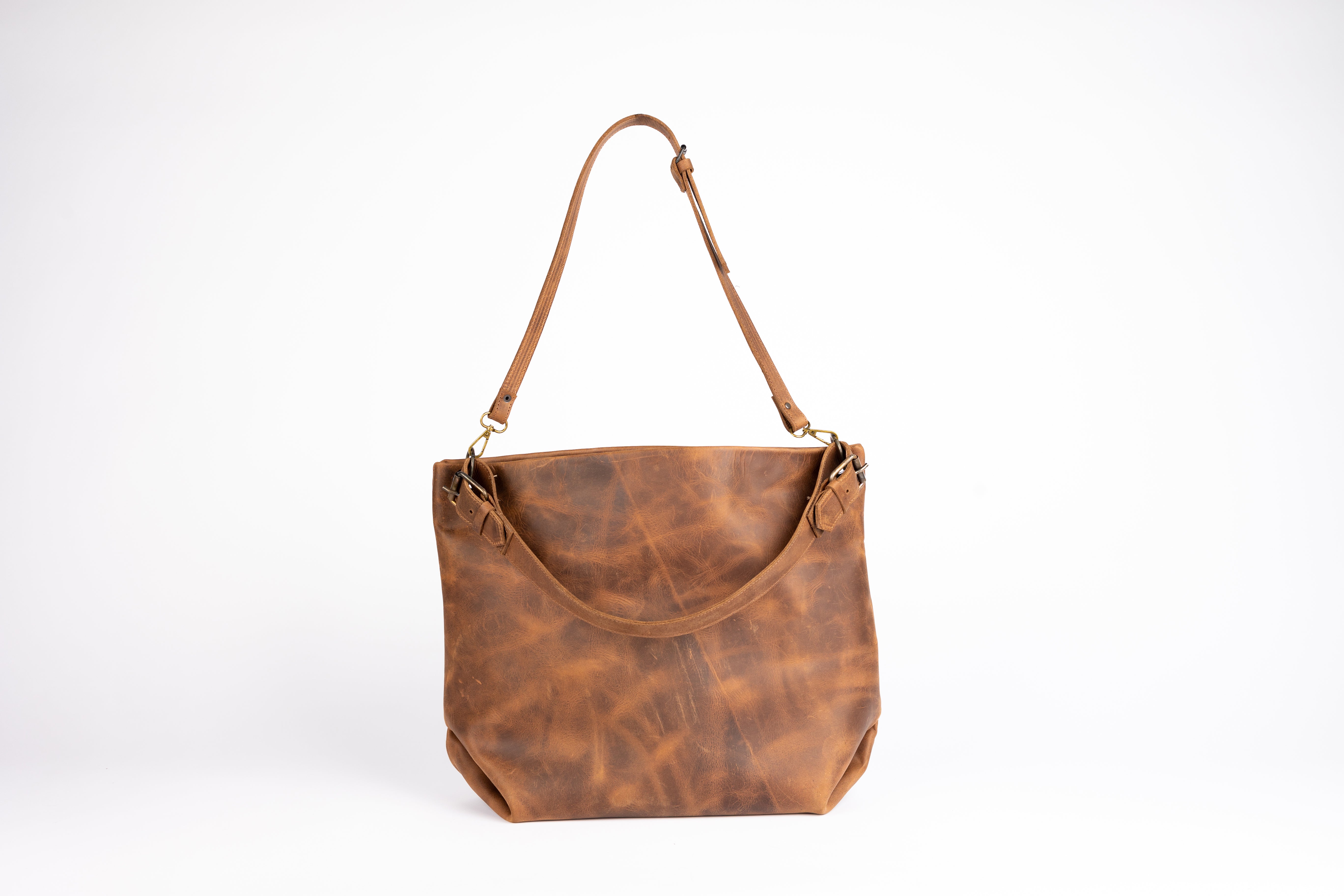 Rear perspective of the Parisian Tote displaying dual side buckles, natural leather creasing, and clean lines. This view captures the back panel’s grain pattern and hand-sewn craftsmanship.